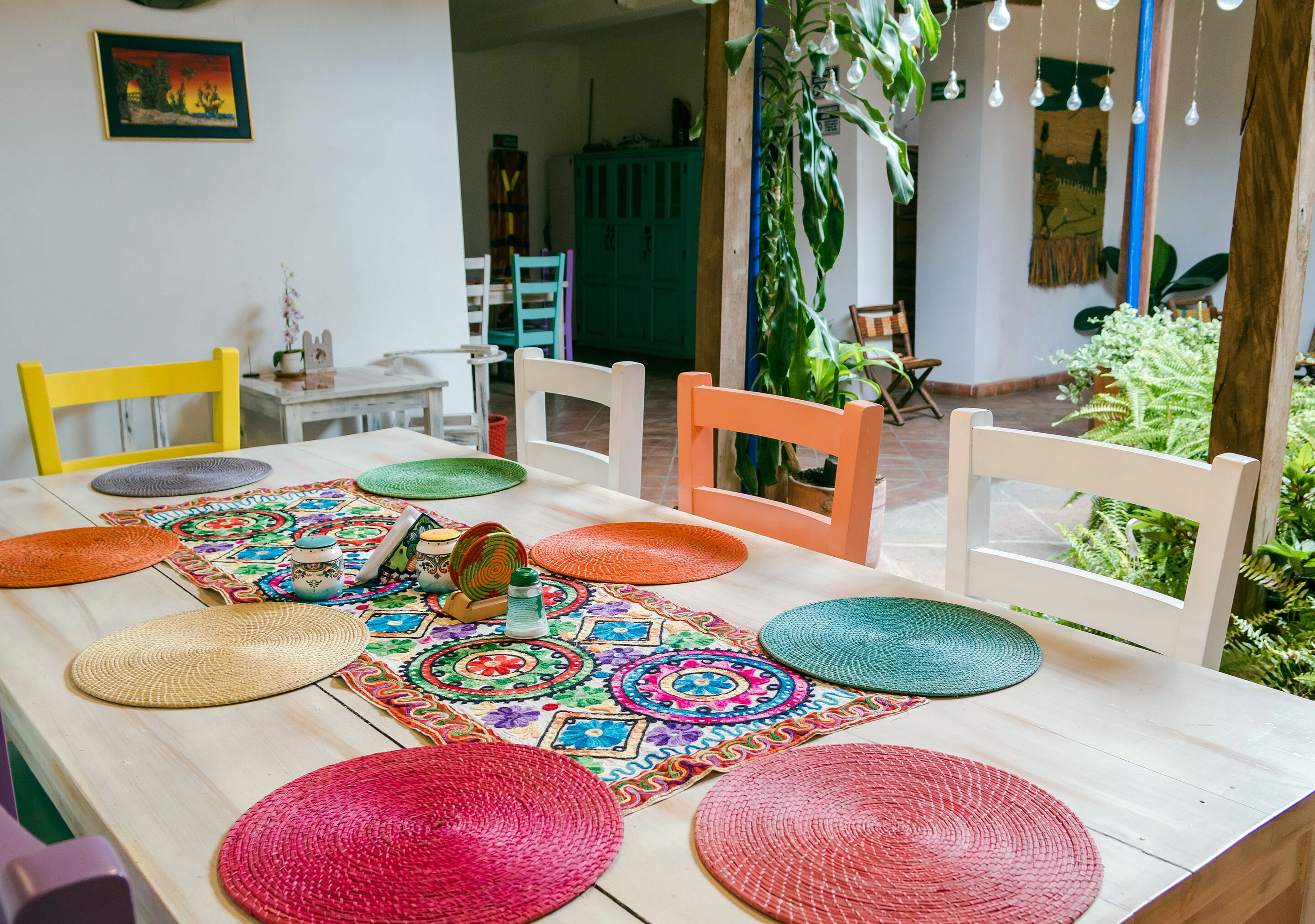 Un tavolo da pranzo con tovagliette colorate intrecciate e sedie.
