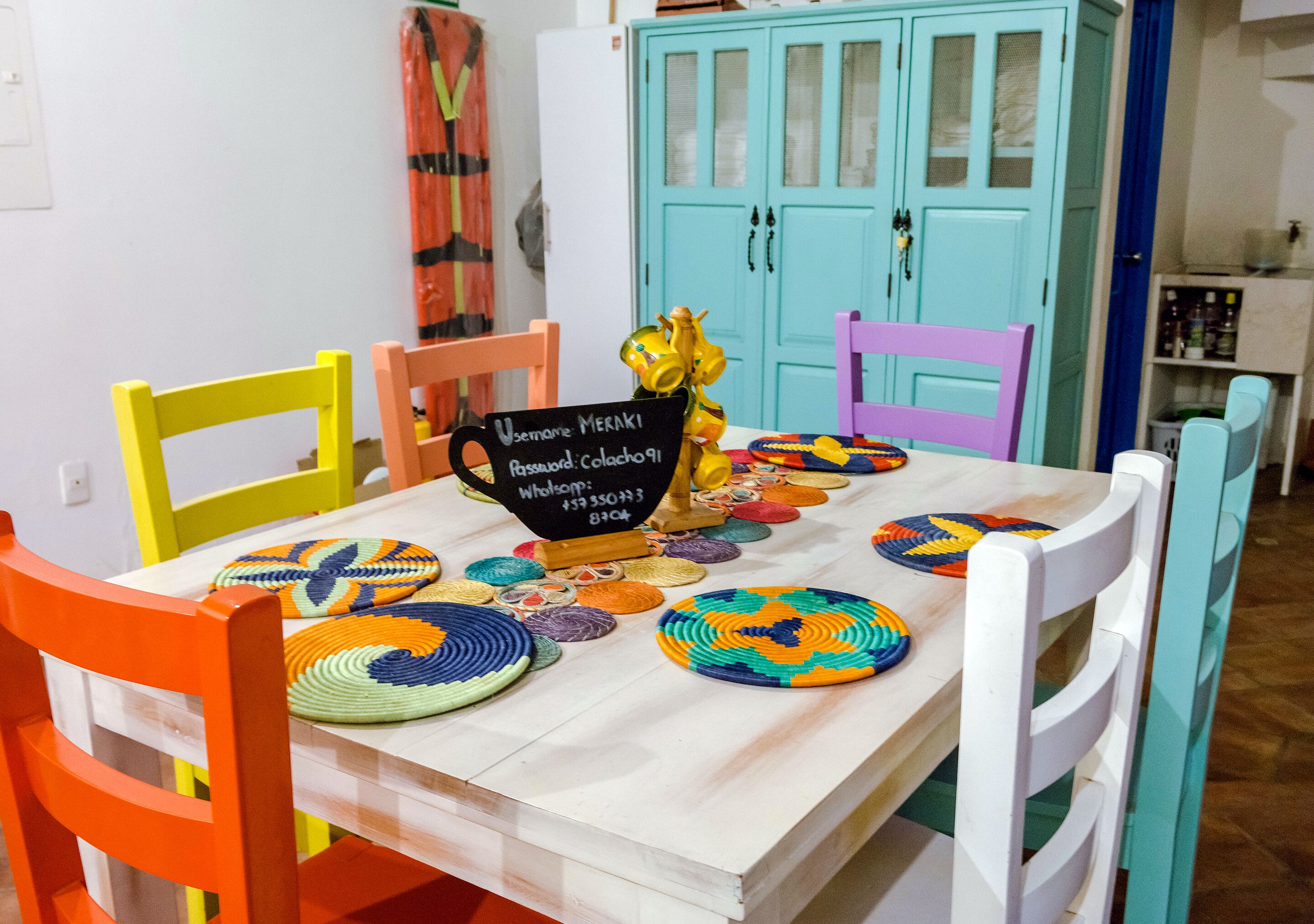 A dining table with colorful woven placemats, a sign with a username and password, and a yellow decorative item.