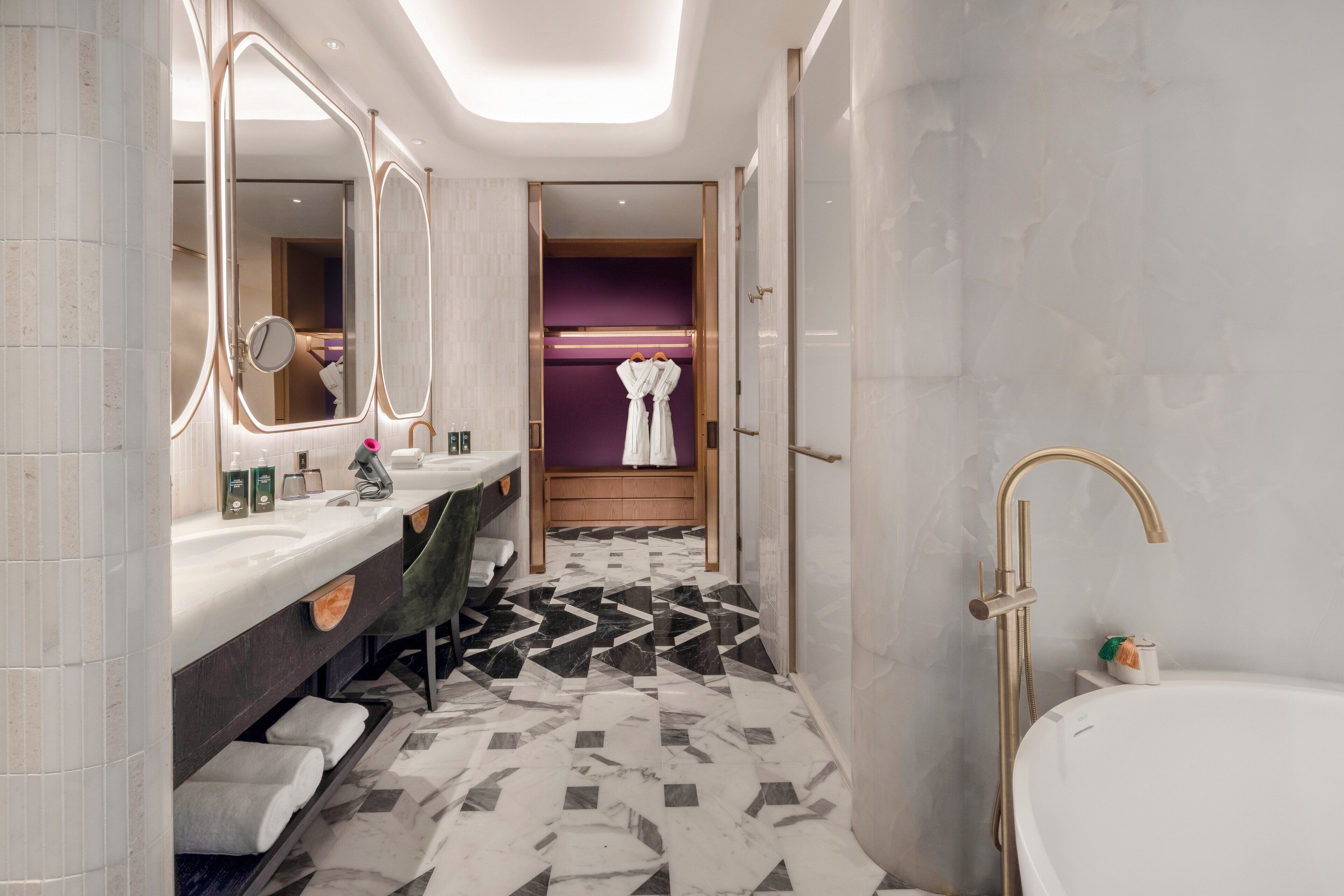 Un baño moderno con tocador, espejos grandes, bañera y ducha.