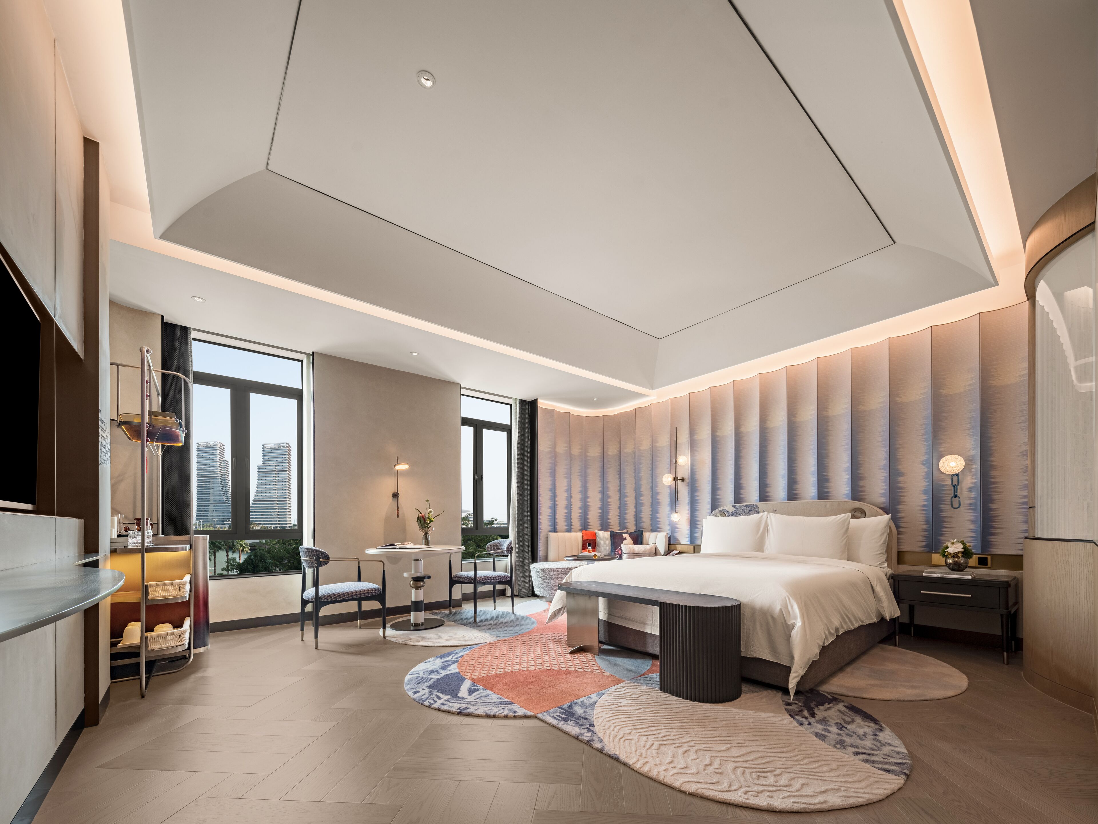 A modern hotel room with a large bed, a desk, and a seating area.