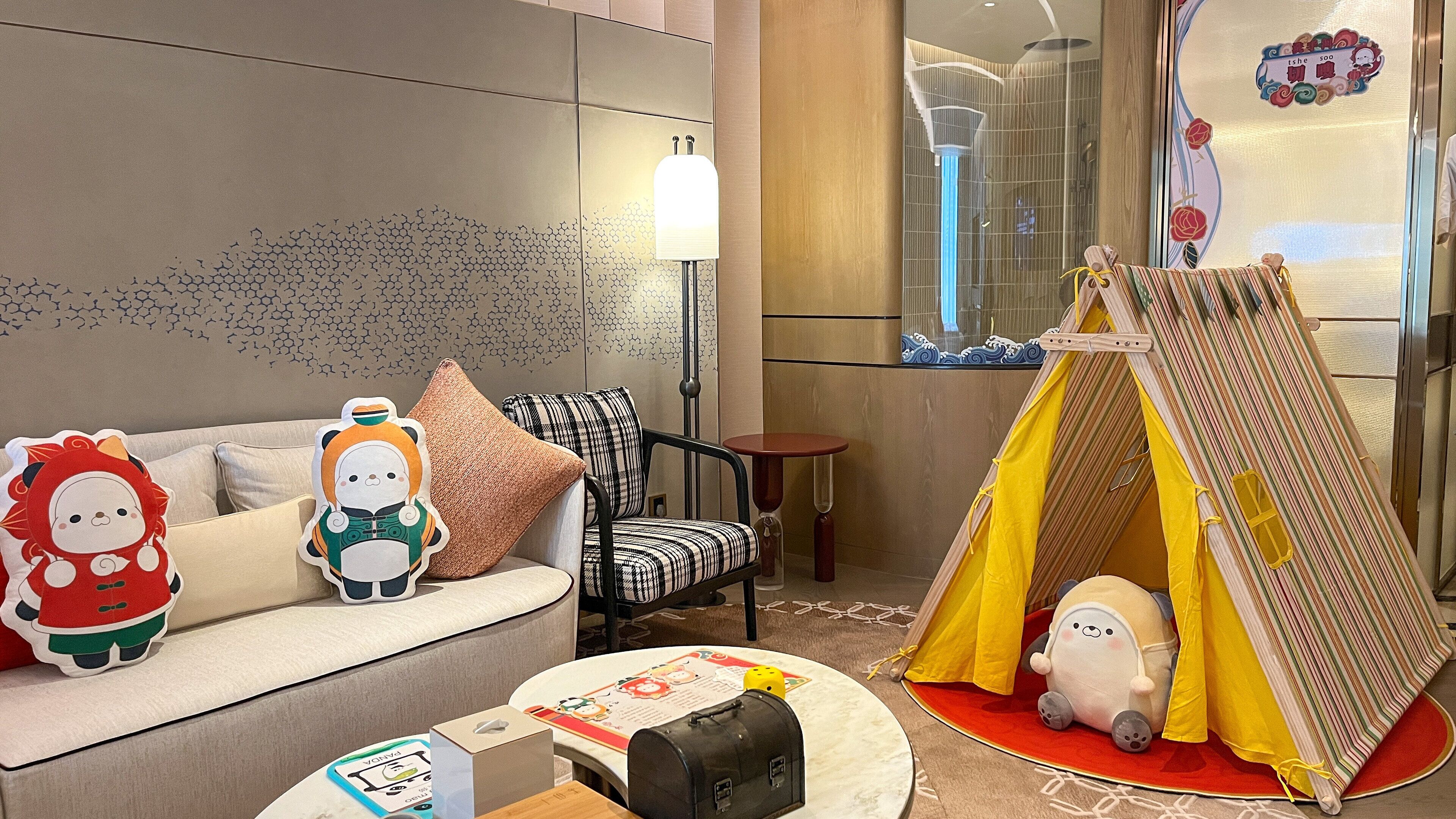 A cozy hotel room with a sofa, a play tent, and a lamp.