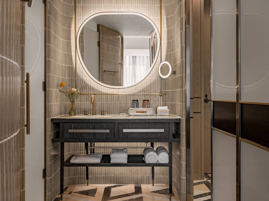 A modern bathroom with a vanity, a large mirror, and a patterned floor.