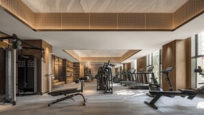 Ett modernt gym med en mängd olika träningsredskap, stora fönster och ett högt tak med en unik design.
