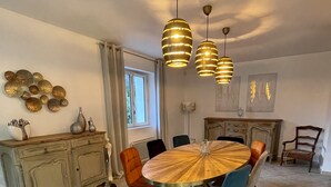 A dining area with a round wooden table, multiple chairs, a cabinet, and pendant lights. - House La Luberonne Gordes Vaucluse Provence. Heated pool from May 15. (Gordes)