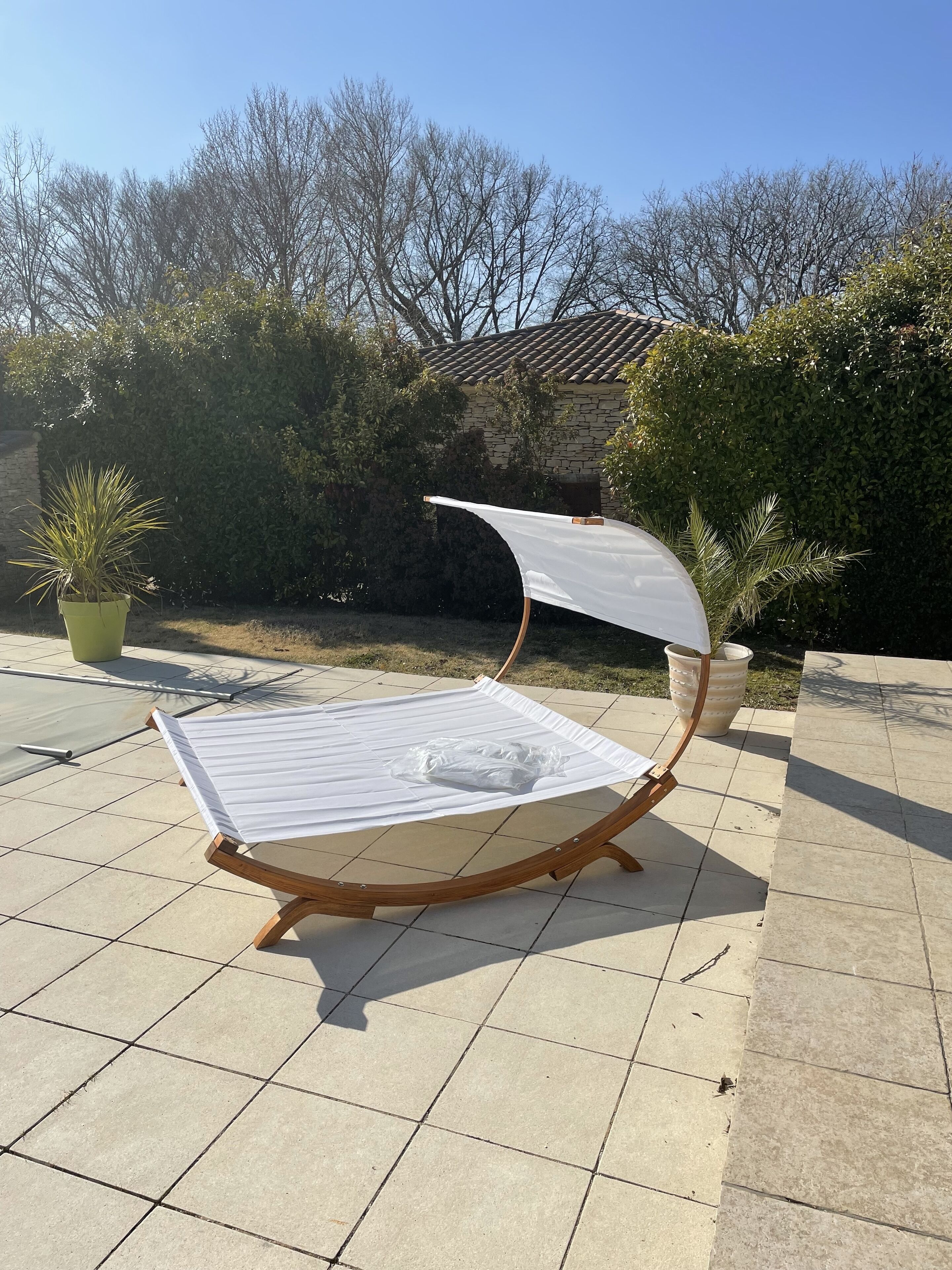 Una poltrona da esterno con tenda bianca, posizionata su un patio piastrellato.