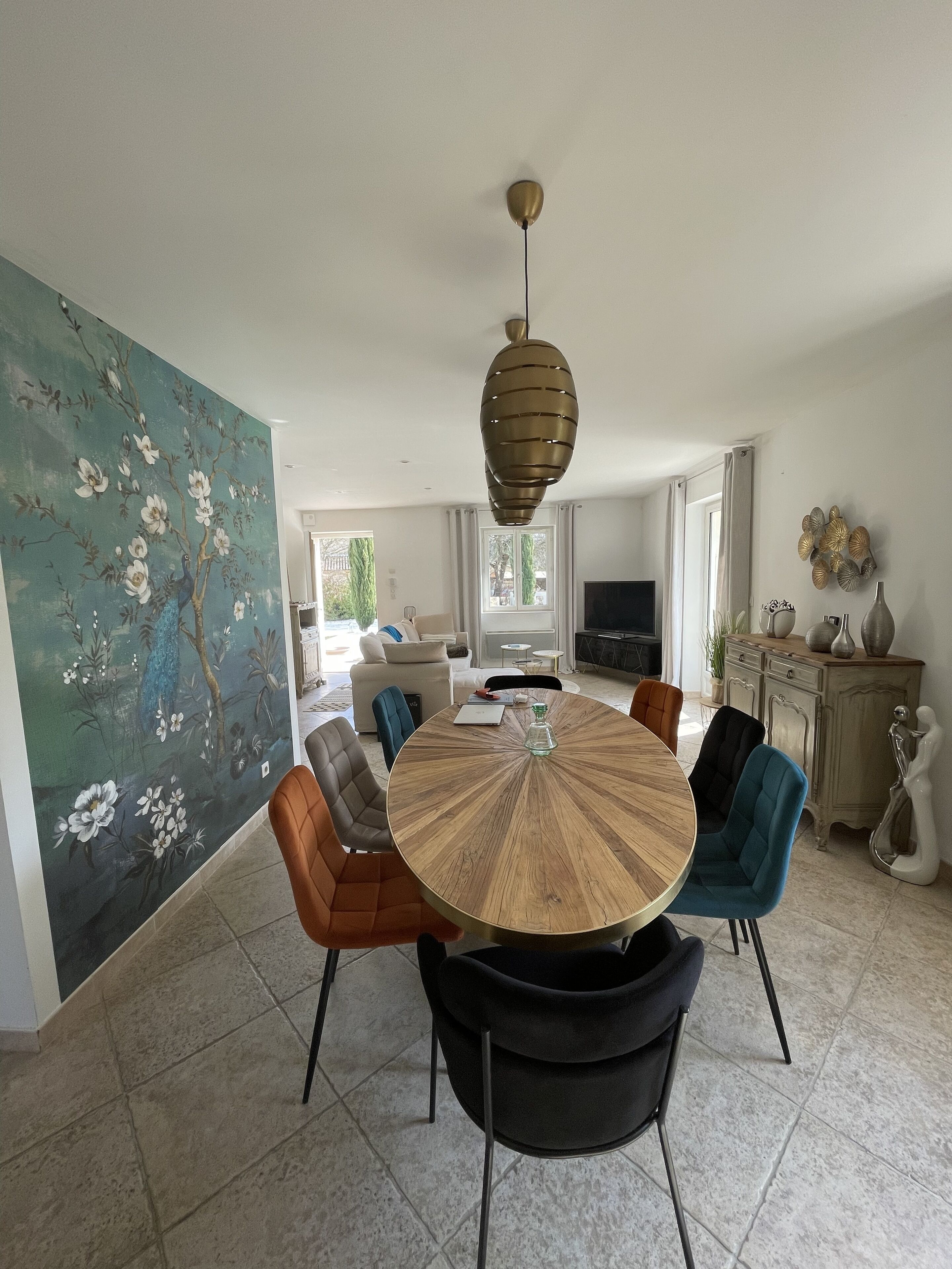 A dining area with a round wooden table, modern chairs, and a decorative hanging light fixture.
