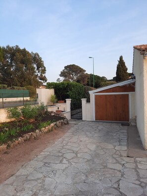 residence with a paved driveway, garage, and lush greenery.