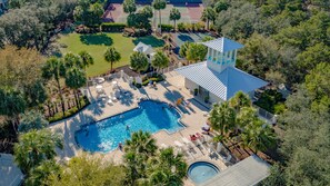 Vista aérea de un complejo turístico con piscina, zona de descanso y canchas de tenis.