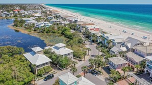 Una zona residencial costera con casas a lo largo de la playa, vistas despejadas del océano y una carretera que conduce a la playa.