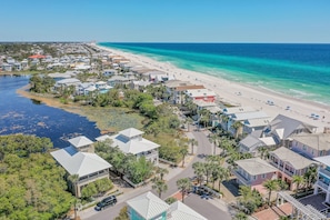 Una zona residencial costera con casas a lo largo de la playa, vistas despejadas del océano y una carretera que conduce a la playa.