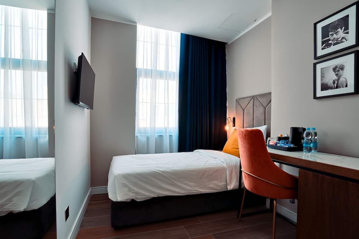A hotel room with two beds, a desk with a chair, a flat-screen TV, and framed pictures on the wall.