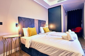 Habitación de hotel con dos camas, una mesa redonda y una silla roja.