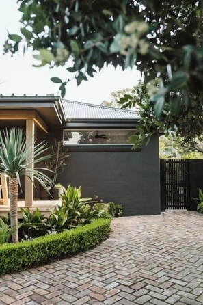 A modern house with a brick pathway leading to a wooden door. - Dunes on Sandy Wha (Gerringong)