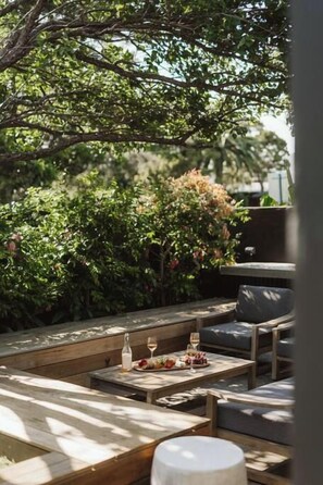An outdoor seating area with wooden furniture and a table set with food and drinks. - Dunes on Sandy Wha (Gerringong)