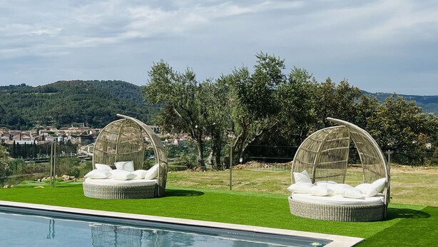 Zona de piscina con dos cabañas de mimbre y una pileta.