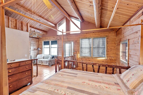 A wooden cabin bedroom with a bed, dresser, and two windows. - Authentic log cabin - Short drive to Fredericksburg - Hill Country Views (Fredericksburg)