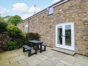 A stone building with a patio, a table, and benches.