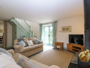 A living room with a sofa, television, and a staircase.