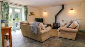 Una sala de estar con sofá, sillones, televisor, chimenea y puerta que da al exterior.