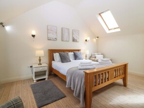 Une chambre à coucher avec un lit en bois, des tables de chevet, un banc, un tapis gris et une lucarne.