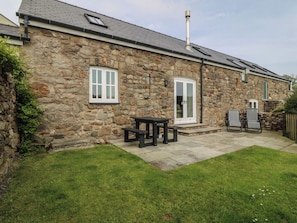A stone building with a patio, a table, and two chairs.