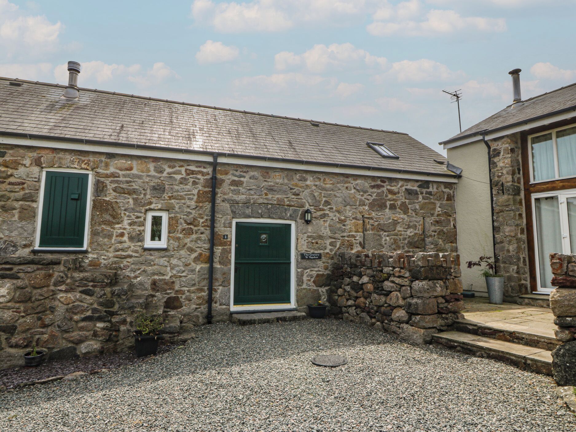 A stone building with a green door, a small window, and a sign that reads 'The Grange.'