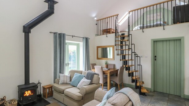 Un salon chaleureux avec un canapé, une table, un escalier et une porte verte.