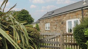 Un bâtiment en pierre avec une porte, une fenêtre et un portail en bois.