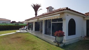 A single-story house with a covered patio, large sliding glass doors, and a small garden area.