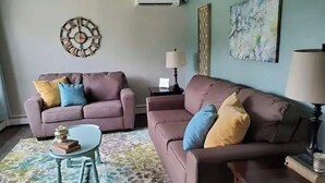 Uma sala de estar com dois sofás, uma mesinha e um tapete estampado.
