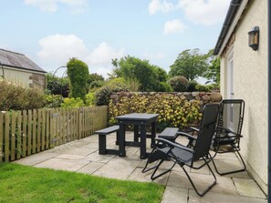 A patio with a table and chairs, a stone wall, and a wooden fence. - No 3 The Dairy (Llangefni)
