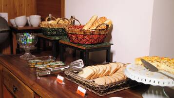 Une table de buffet proposant divers aliments, notamment du pain, des pâtisseries et un gâteau.