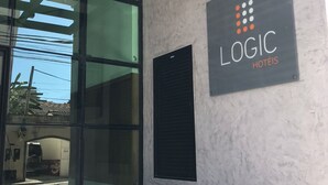 Una entrada de hotel moderna con fachada de vidrio, un letrero que dice "LOGIC HOTÉIS" y el número "95" en la pared.