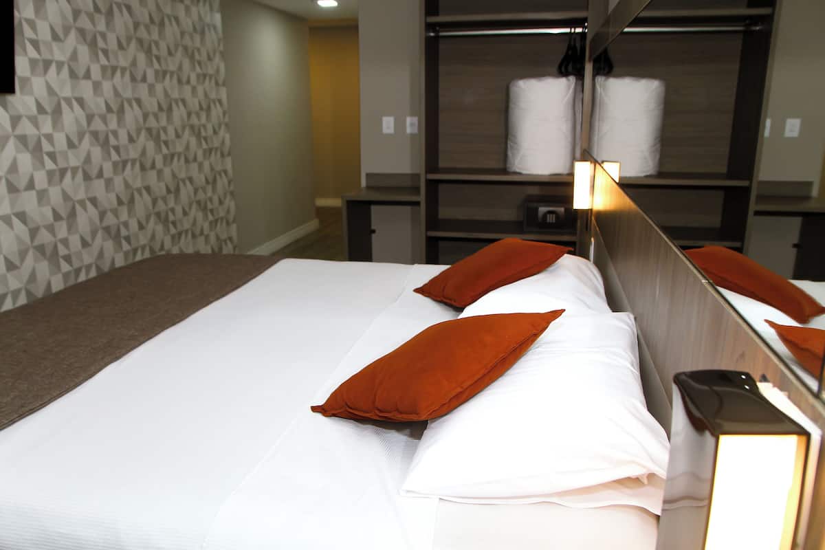 Una habitación de hotel con una cama bien hecha, un papel tapiz estampado y un estante con toallas.