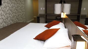 Una habitación de hotel con una cama bien hecha, un papel tapiz estampado y un estante con toallas.