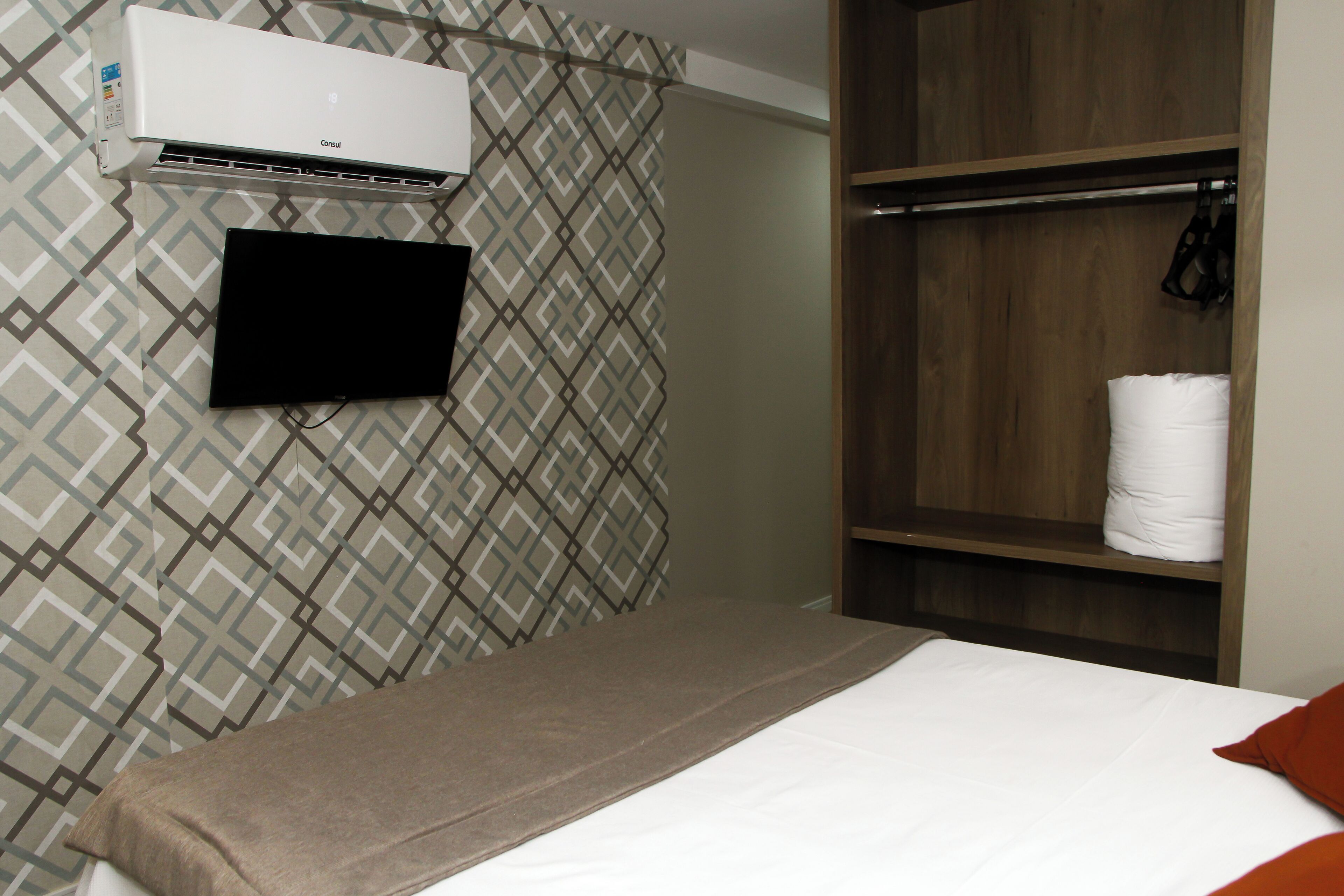 Une chambre d’hôtel équipée d’un lit, d’un téléviseur fixé au mur, d’une armoire et d’un appareil de climatisation.