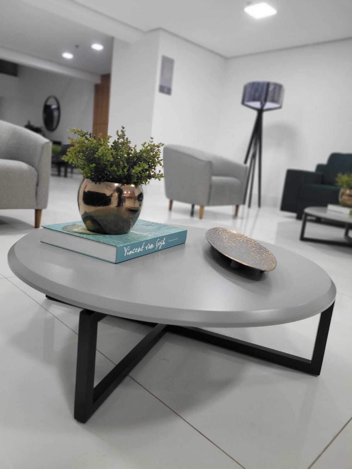 A modern living room with a round table, a potted plant, and a book titled "Vincent van Gogh".