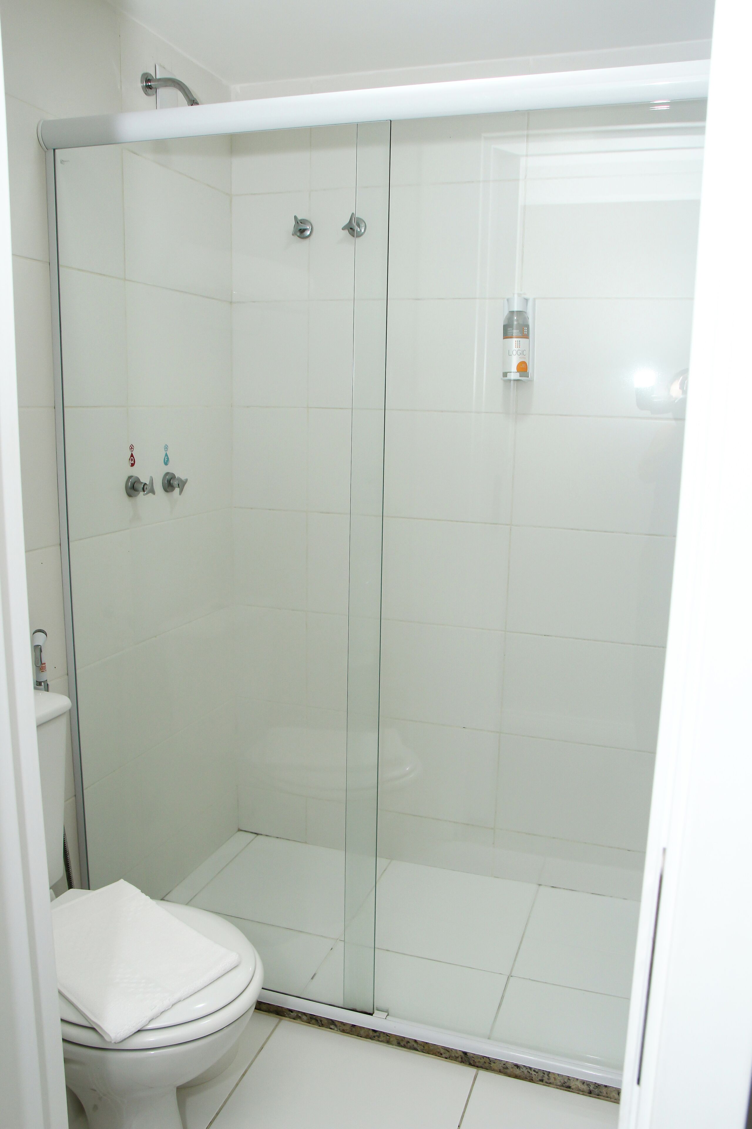 Ein Duschraum mit Glaswand und Toilette links.