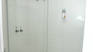Ein Duschraum mit Glaswand und Toilette links.