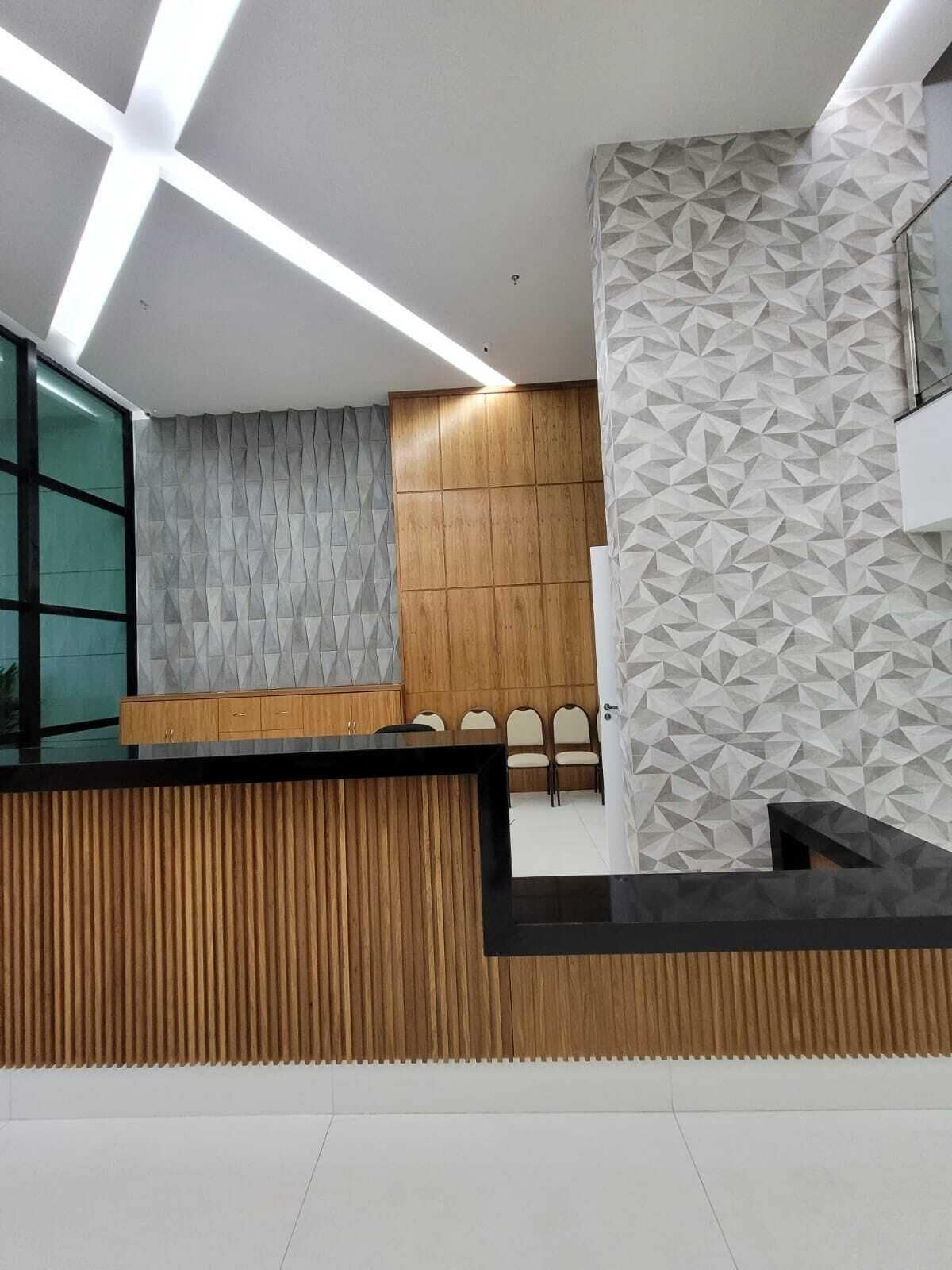 Ett modernt receptionsområde med en receptionsdisk i trä, en vägg med geometriskt mönster och en glasvägg.