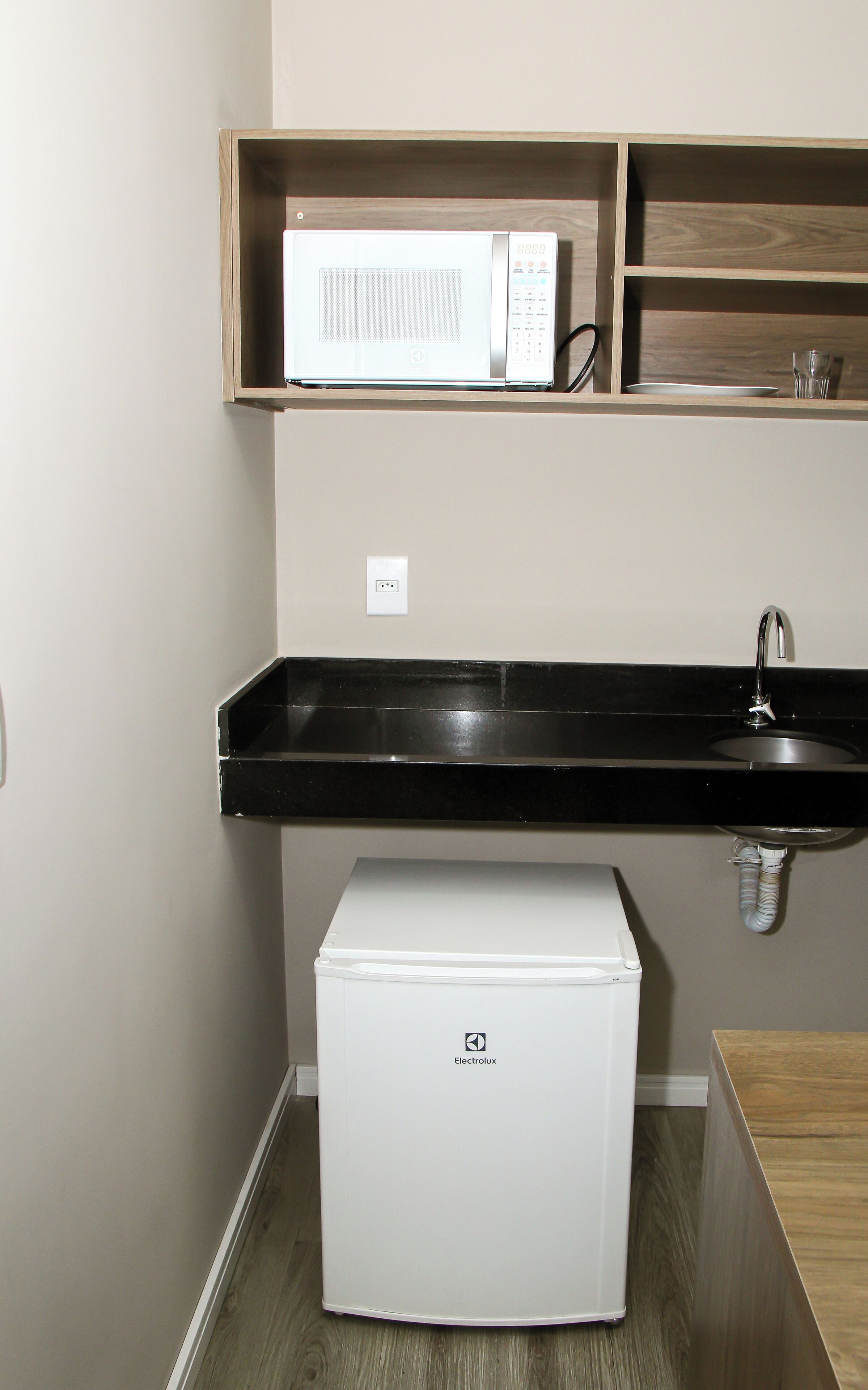 A compact kitchenette with a microwave, sink, and refrigerator.