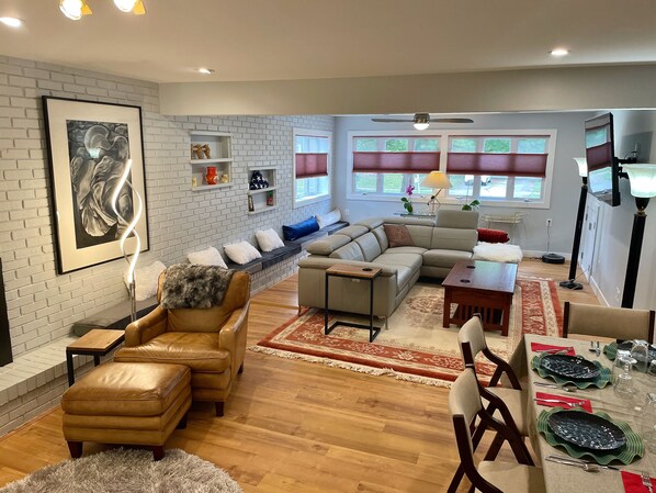 A modern living room with a sectional sofa, a coffee table, and a dining area set for four. - Bloomington Indiana Rental- 2BR/1BA Apartment on ground floor of duplex (Bloomington)