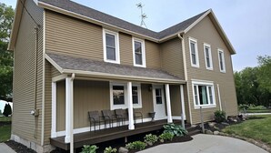 Une maison à deux étages avec un porche couvert, une cheminée et une antenne parabolique.