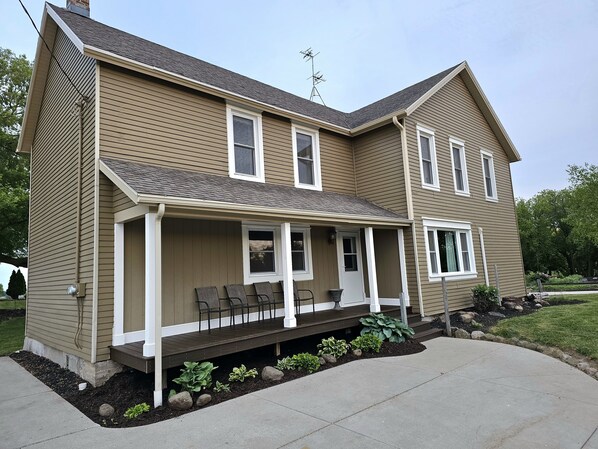 A two-story house with a covered porch, a chimney, and a satellite dish.