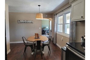 Enjoy meals in the dining area with a round table and four chairs, surrounded by a kitchen and a view into another room.