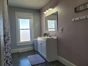 Bathroom features a single vanity, mirror, and window with an outdoor view.