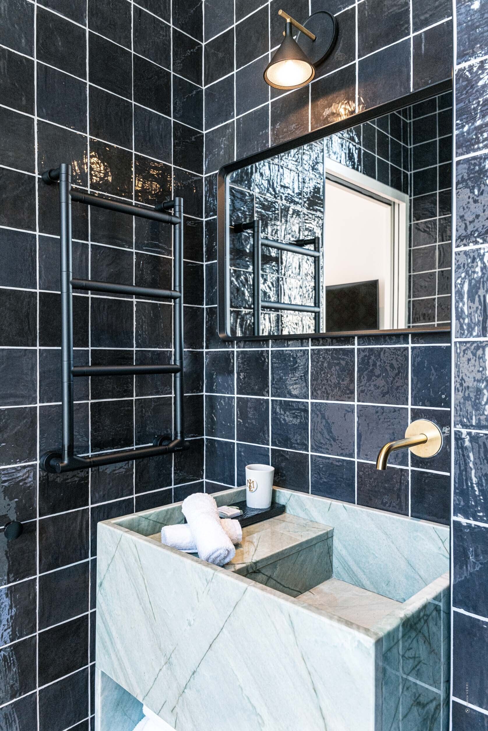 Une salle de bain avec un lavabo en marbre, un porte-serviettes, un miroir et une serviette posée sur le comptoir.