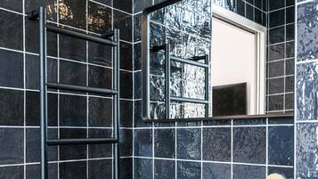 Une salle de bain avec un lavabo en marbre, un porte-serviettes, un miroir et une serviette posée sur le comptoir.