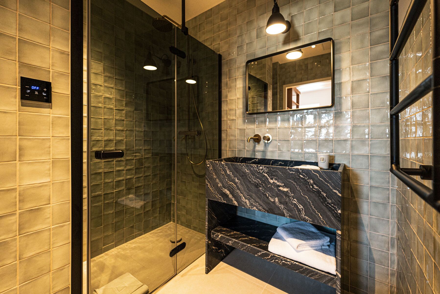 A modern bathroom with a glass-enclosed shower, a marble sink, and a mirror above the sink.