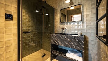 A modern bathroom with a glass-enclosed shower, a marble sink, and a mirror above the sink.